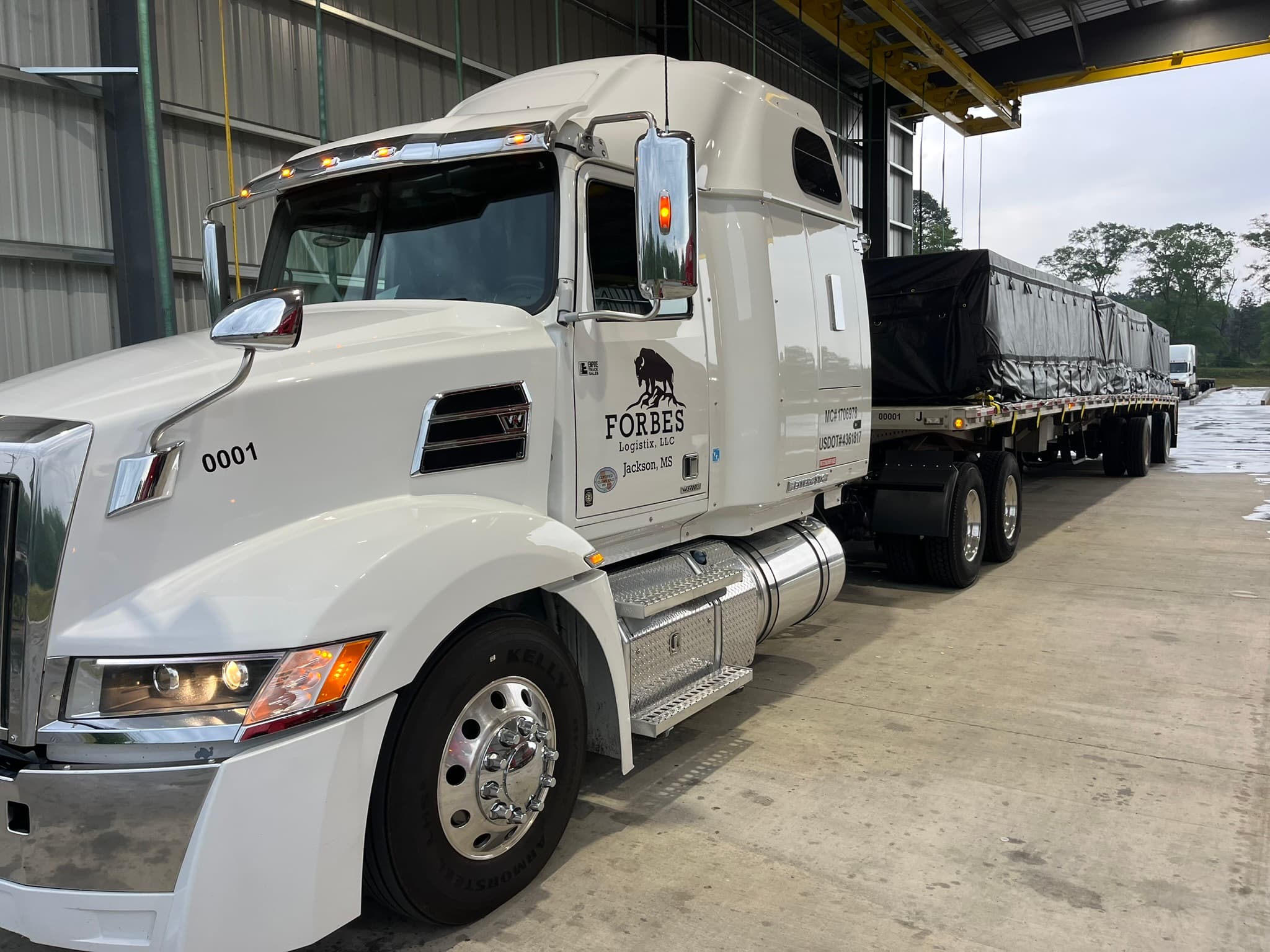 Forbes Logistix Western Star tractor with open-deck trailer under covered loading area